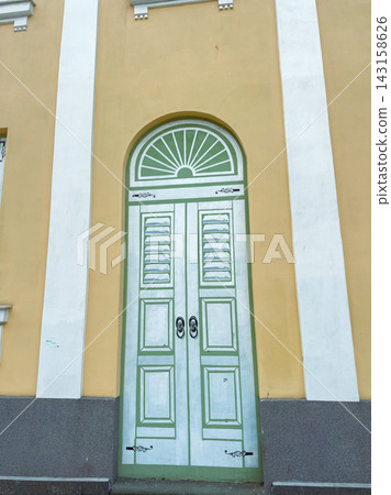 Historic door on a building with yellow exterior and green details in an urban area 143158626