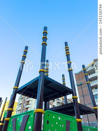 Modern playground structure stands under a clear blue sky in a city setting, showcasing its unique design and vibrant colors Modern playground structure stands under a clear blue sky in a city setting, showcasing its unique design and vibrant colors 143158744