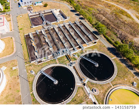 Water treatment facility in operation with multiple tanks and equipment visible from above during daytime 143158759