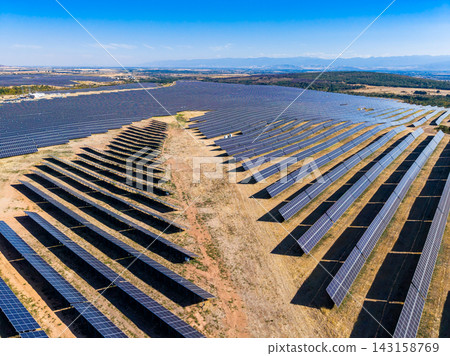 Large solar panel farm under bright sun in a clear blue sky with mountains in the background Large solar panel farm under bright sun in a clear blue sky with mountains in the background 143158769
