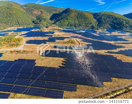 Solar energy field spreads across a valley surrounded by mountains with clear blue sky in view during daytime Solar energy field spreads across a valley surrounded by mountains with clear blue sky in view during daytime 143158771