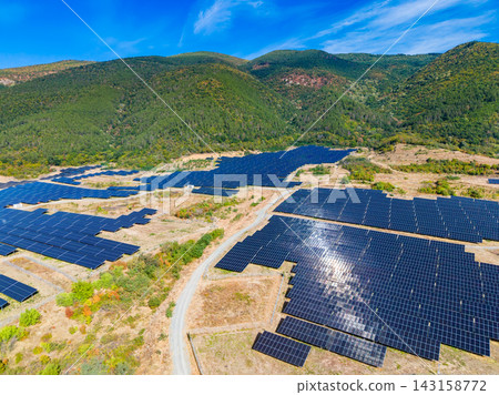 Solar panels cover a large area in a valley surrounded by mountains under a clear blue sky on a sunny day Solar panels cover a large area in a valley surrounded by mountains under a clear blue sky on a sunny day 143158772