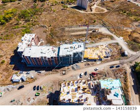 Construction of residential buildings in an urban area with vehicles and cranes present during a sunny day Construction of residential buildings in an urban area with vehicles and cranes present during a sunny day 143158839