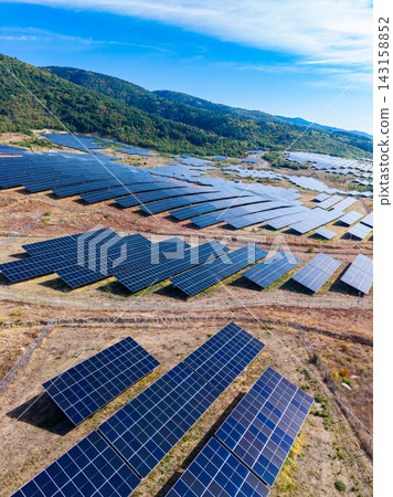 Solar panels cover a large field in a rural area under a clear blue sky during daytime 143158852