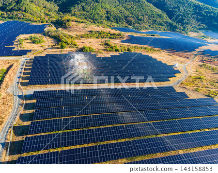 Solar panels cover a large area in a renewable energy farm near the mountains on a clear sunny day Solar panels cover a large area in a renewable energy farm near the mountains on a clear sunny day 143158853