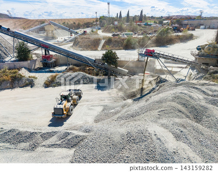 Work taking place at a granite quarry with machinery and stone processing in the background Work taking place at a granite quarry with machinery and stone processing in the background 143159282