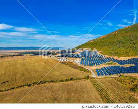 Solar panel installation in a field near a mountain under a clear blue sky Solar panel installation in a field near a mountain under a clear blue sky 143159286