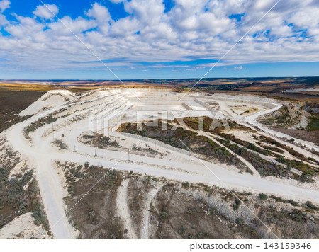 Quarry landscape showing extraction area and surrounding terrain in bright daylight Quarry landscape showing extraction area and surrounding terrain in bright daylight 143159346
