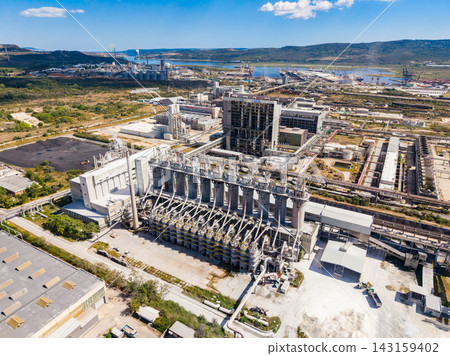 Industrial facility located in an industrial area near the coast, showcasing machinery and structures under a clear blue sky during daytime hours 143159402