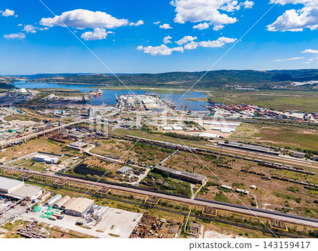 Landside view of a busy harbor area with shipping containers and industrial buildings on a sunny day Landside view of a busy harbor area with shipping containers and industrial buildings on a sunny day 143159417
