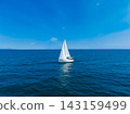 Sailing on clear blue water with a white sailboat under a bright sky in the middle of the ocean on a sunny day 143159499