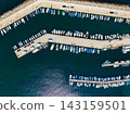 Harbor with many boats docked during daytime in a coastal area 143159501