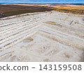 Quarry in a large open area showing layers of earth and machinery observed from above during the day 143159508