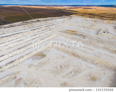 Quarry in a large open area showing layers of earth and machinery observed from above during the day Quarry in a large open area showing layers of earth and machinery observed from above during the day 143159508