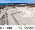 Quarry site with large area showing excavated land and equipment under clear sky at midday 143159509