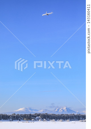 北海道千歲市：遠處雪原上聳立著樽前岳和伏伏岳，一架飛機正飛往新千歲機場。 [二月] 143160411