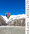 A landscape of colorful hot air balloons flying against a blue sky over snow-covered mountains (top copy space, vertical orientation) 143161270
