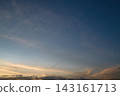 Dramatic sunset sky with layered dark clouds and illuminated airplane contrails crossing a blue and orange horizon. 143161713