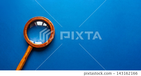 Vintage wooden magnifying glass with brass ring on vibrant blue background Vintage wooden magnifying glass with brass ring on vibrant blue background 143162166