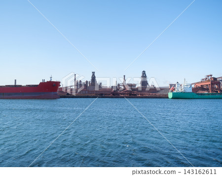 Cargo ship loading steel products at a port near a heavy industrial metallurgical plant. Cargo ship loading steel products at a port near a heavy industrial metallurgical plant. 143162611