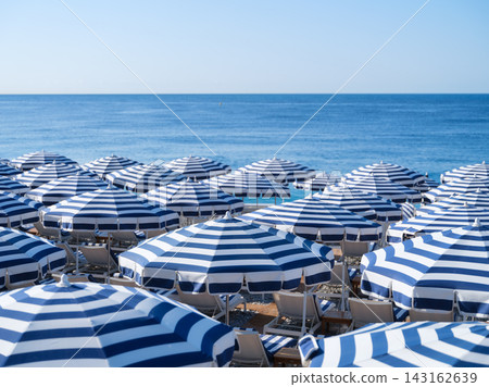 Sun umbrellas and sunbeds on a sandy beach by the sea.  143162639