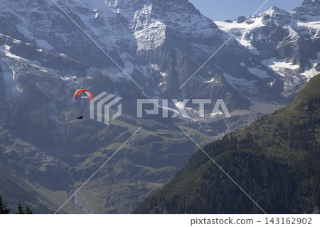 Paraglider flying over mountains in swiss alps Paraglider flying over mountains in swiss alps 143162902