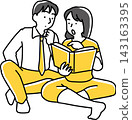 A man looking at a book and a woman pointing to an interesting passage in it. 143163395