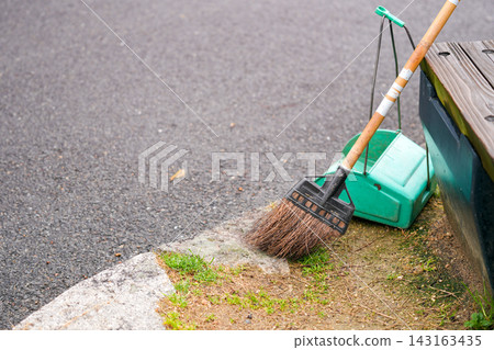 A broom and dustpan placed outdoors A broom and dustpan placed outdoors 143163435