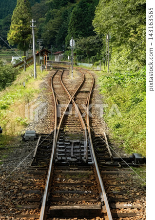 坐落在鬱鬱蔥蔥的青山之中的鄉村火車站和鐵路線。 坐落在鬱鬱蔥蔥的青山之中的鄉村火車站和鐵路線。 143163565