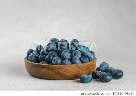 Fresh ripe blueberries in wooden bowl on a light gray textured background. Healthy organic food Fresh ripe blueberries in wooden bowl on a light gray textured background. Healthy organic food 143164496