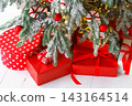 Red wrapped gift boxes, presents under festive Christmas tree with lights and holiday decorations 143164514
