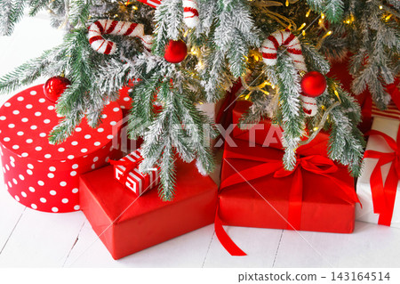 Red wrapped gift boxes, presents under festive Christmas tree with lights and holiday decorations 143164514
