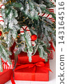 Red wrapped gift boxes, presents under festive Christmas tree with lights and holiday decorations 143164516