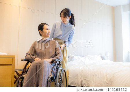一位家長和孩子乘坐輪椅出行 一位家長和孩子乘坐輪椅出行 143165512
