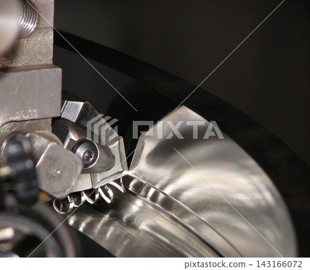 Extreme close-up of an indexable carbide insert cutting tool machining a steel workpiece on a lathe, producing spiral metal swarf chips in a precision metalworking operation. Extreme close-up of an indexable carbide insert cutting tool machining a steel workpiece on a lathe, producing spiral metal swarf chips in a precision metalworking operation. 143166072