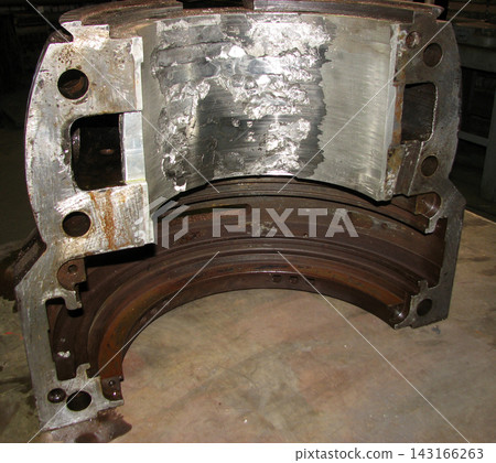 Heavy industrial cast metal bearing housing with damaged inner lining, showing severe wear, pitting, and scoring, prepared for restoration and repair in a factory workshop. Heavy industrial cast metal bearing housing with damaged inner lining, showing severe wear, pitting, and scoring, prepared for restoration and repair in a factory workshop. 143166263