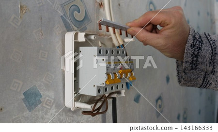 Installation of a comb busbar into an electrical distribution board with circuit breakers during apartment wiring renovation. 143166333