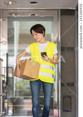 A smiling female delivery person carrying a package. A smiling female delivery person carrying a package. 143166458