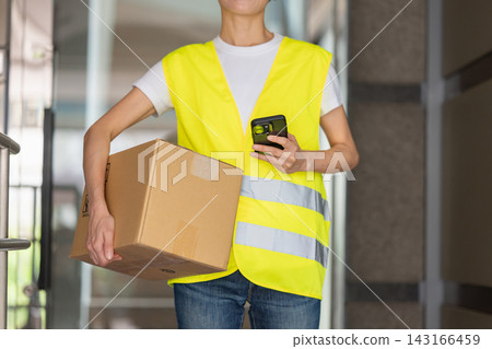A smiling female delivery person carrying a package. 143166459