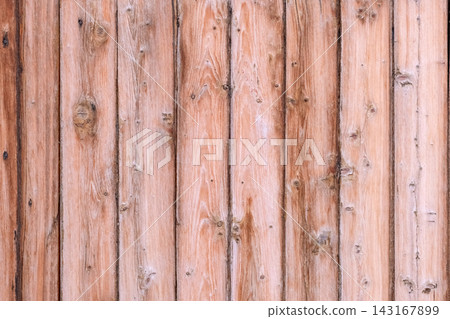 Weathered wooden surface presenting a rustic pattern of vertical timber planks and visible knots, providing a natural background with a warm color Weathered wooden surface presenting a rustic pattern of vertical timber planks and visible knots, providing a natural background with a warm color 143167899