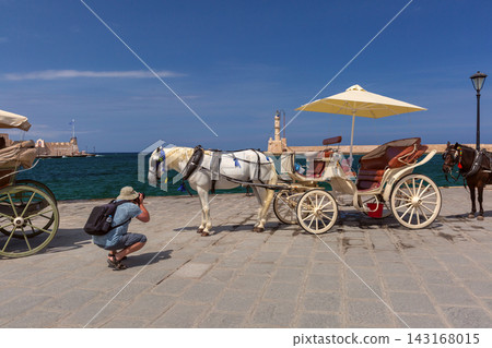 Horse Carriage and Photographer at Chania Old Harbor, Crete, Greece Horse Carriage and Photographer at Chania Old Harbor, Crete, Greece 143168015