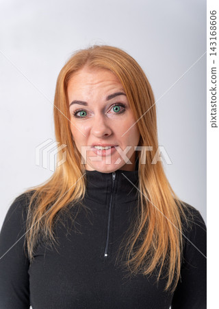 Young woman with red hair and green eyes reacting with a strong negative facial expression, showing feelings of disgust, aversion, and disapproval, isolated on a white background Young woman with red hair and green eyes reacting with a strong negative facial expression, showing feelings of disgust, aversion, and disapproval, isolated on a white background 143168606