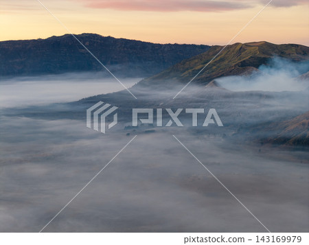 Misty dawn blankets rolling hills in soft, hazy embrace Misty dawn blankets rolling hills in soft, hazy embrace 143169979