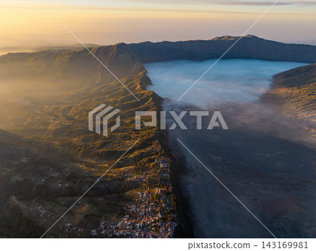 Golden light bathes mist covered volcanic caldera Golden light bathes mist covered volcanic caldera 143169981