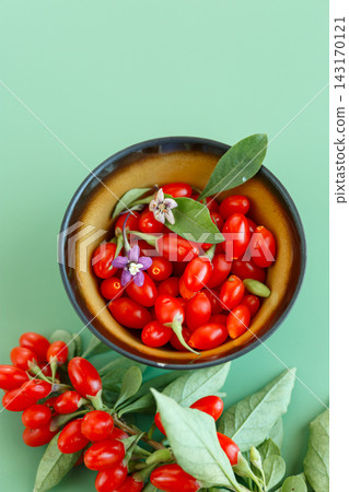 Fresh goji berries and flowers arranged on green background Fresh goji berries and flowers arranged on green background 143170121