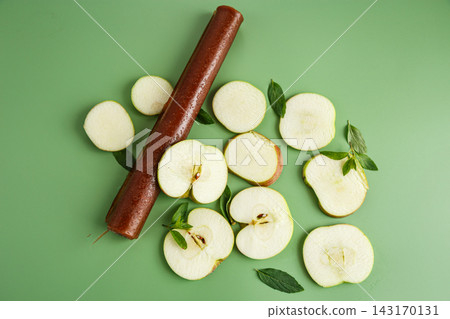 Natural apple fruit leather rolls with mint on green background Natural apple fruit leather rolls with mint on green background 143170131