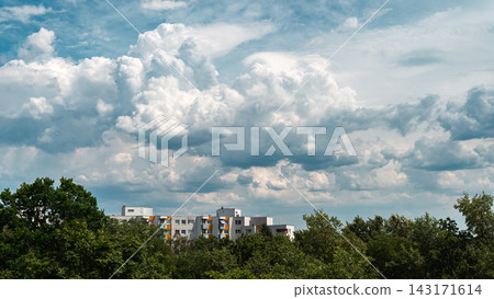 Dramatic Cumulus Clouds Above Residential Buildings and Trees 143171614