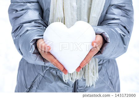 Person holding heart-shaped snow in hands while wearing silver winter coat and white scarf Person holding heart-shaped snow in hands while wearing silver winter coat and white scarf 143172000