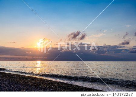 setting sun in dark blue sky over sea and beach setting sun in dark blue sky over sea and beach 143172257
