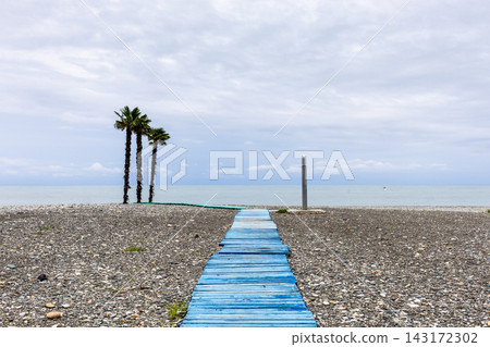 pebble beach with blue wooden boardwalk in Batumi pebble beach with blue wooden boardwalk in Batumi 143172302